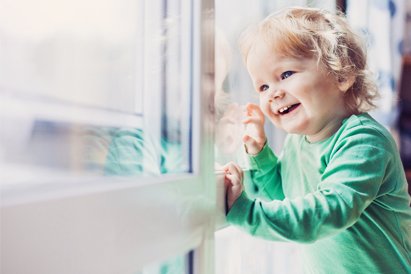 child stands close to window and may fall